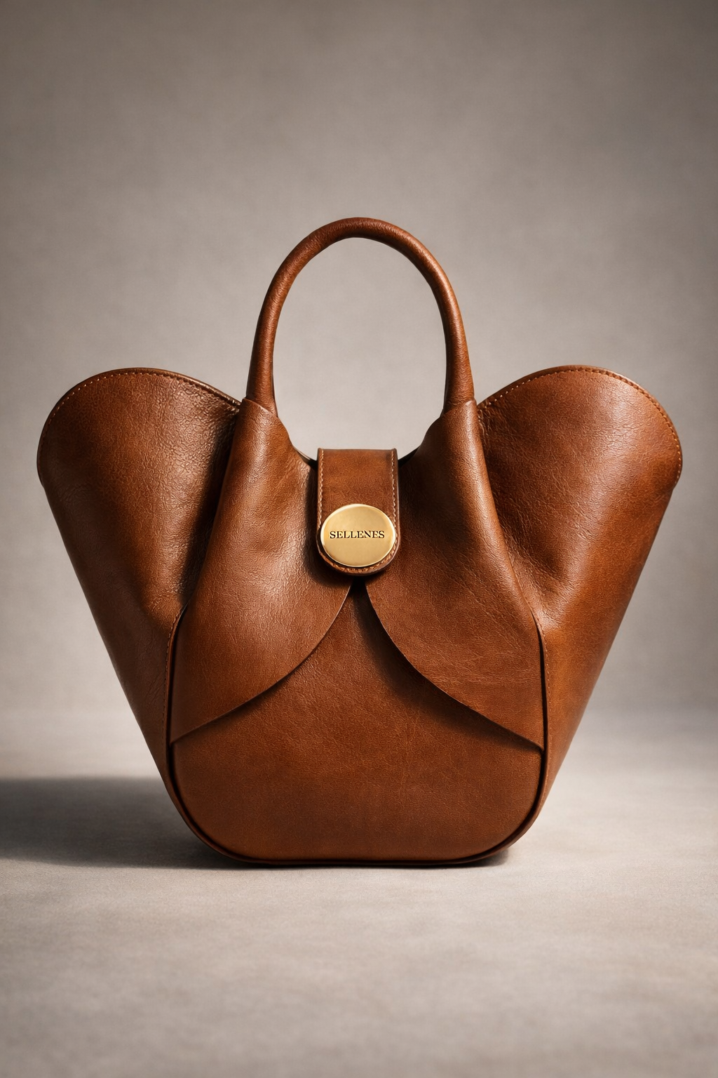Sellenes Aalyah reddish-brown leather tote featuring an organic structured design and central strap with a gold Sellenes button
