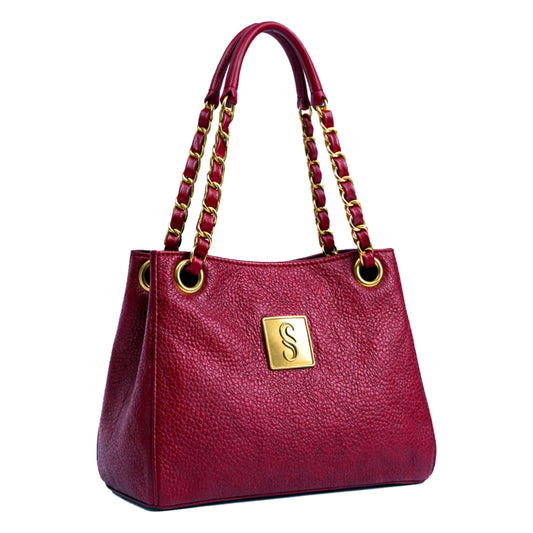 Sellenes Thea designer handbag in Cremisi red pebble-grain leather, accented with a luxury gold-plated 'S' logo plate on the front. This high-end shoulder bag features elegant gold-tone chain and leather interwoven straps and refined tonal stitching.